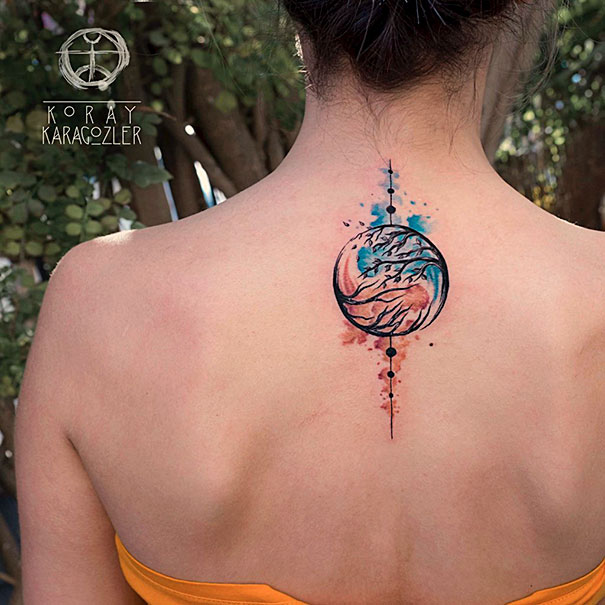 Colorful spine tattoo featuring a circular tree design on a woman's back outdoors.