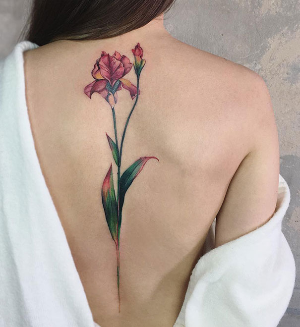 A vibrant flower spine tattoo on a woman's back, showcasing intricate design and artistry.