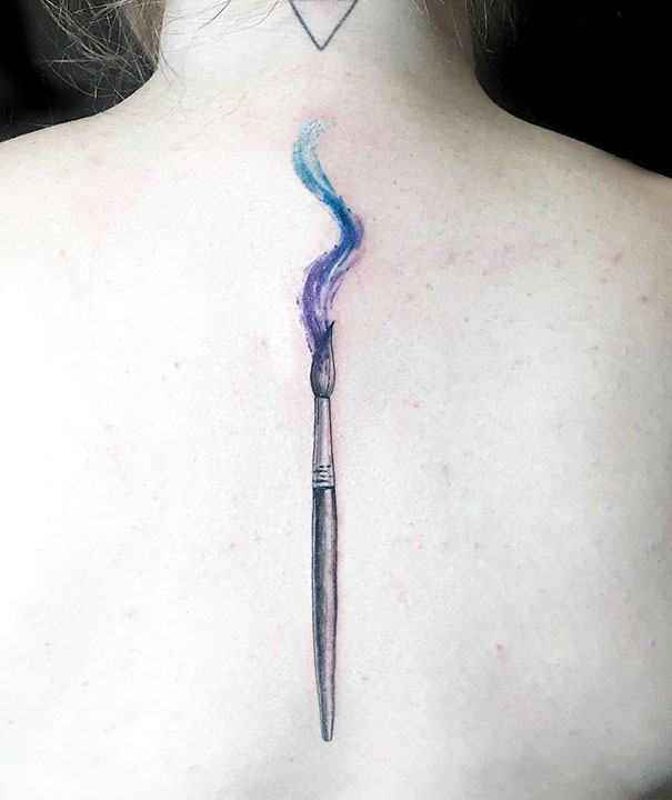 Watercolor brush spine tattoo with blue and purple swirls.