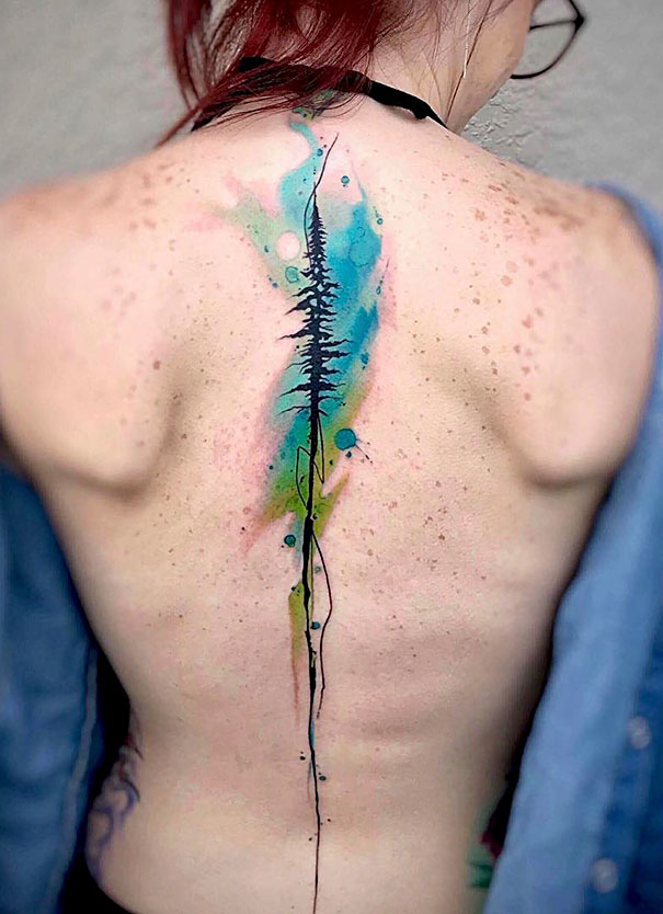 Woman with colorful spine tattoo featuring abstract watercolor design.