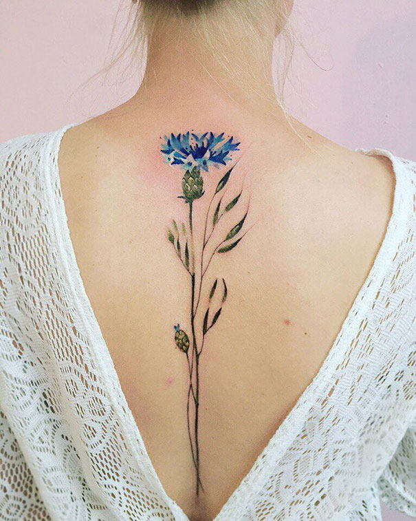 Floral spine tattoo on woman's back with open lace dress.