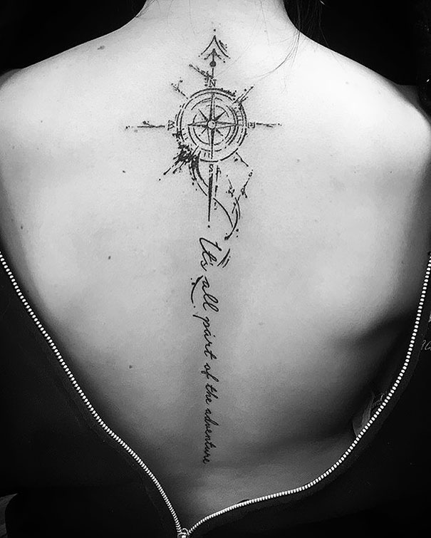 Compass design spine tattoo with script on a person's back.