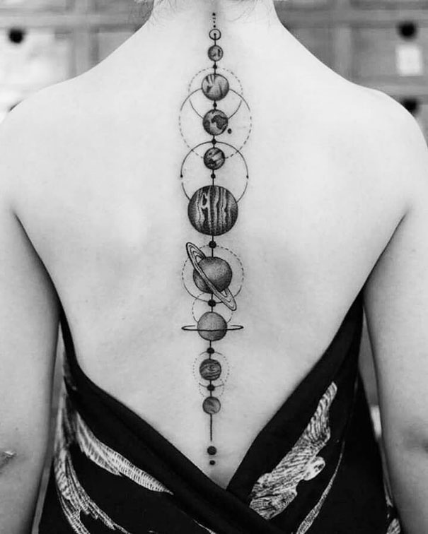 Spine tattoo of a solar system design with planets and orbits in black ink.