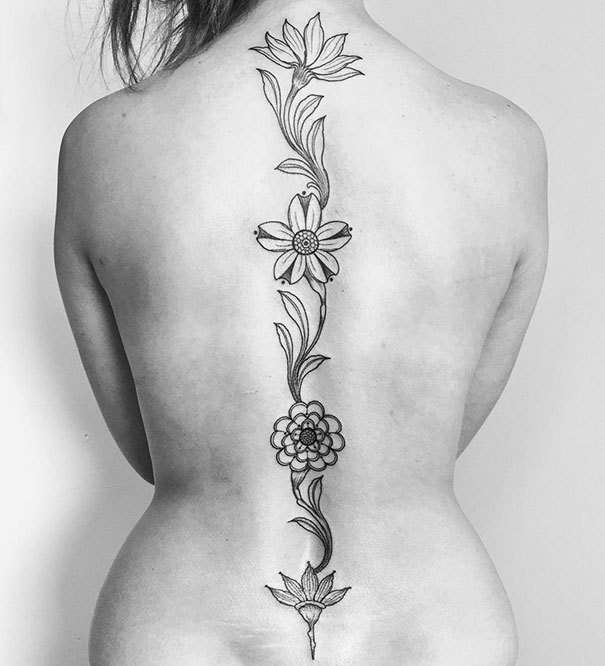 Floral design spine tattoo on a woman's back, showcasing intricate flower patterns.