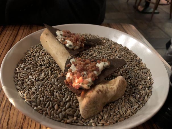 Crackers With Fried Ham And Dressing, Served On A Bone Resting On Barley Grain In A Bowl