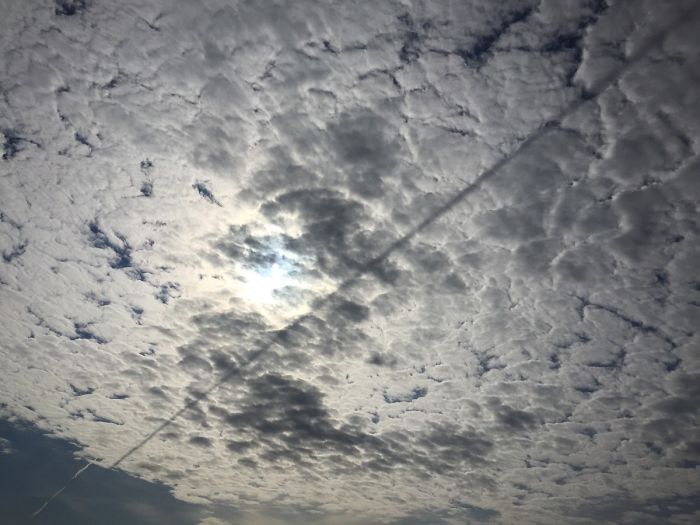 The Contrail Of A Jet Cast A Shadow On The Clouds Below