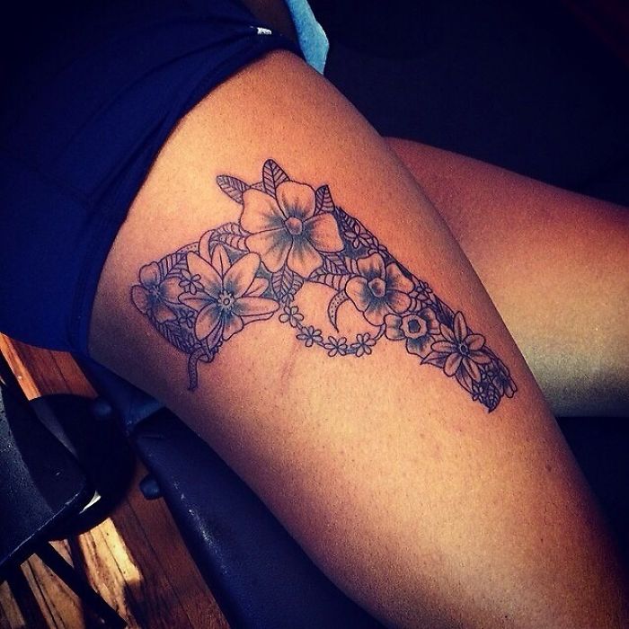 Tattoo artist skillfully interprets client's wish with a floral design on thigh.
