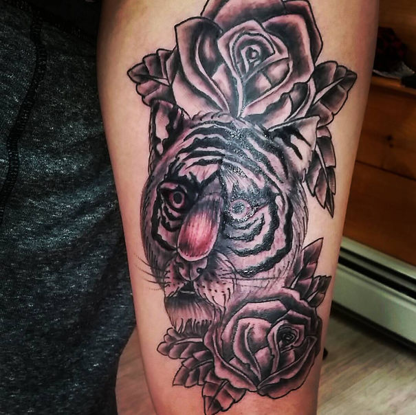 Tiger tattoo with distorted face and roses on thigh, showcasing a tattoo fail.