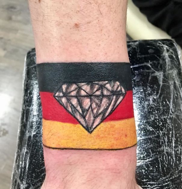 Bad tattoo fail with a diamond on a German flag wristband.