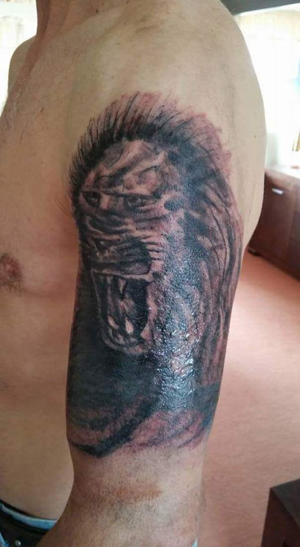 Bad tattoo fail depicting an unrecognizable lion face on a person's arm.