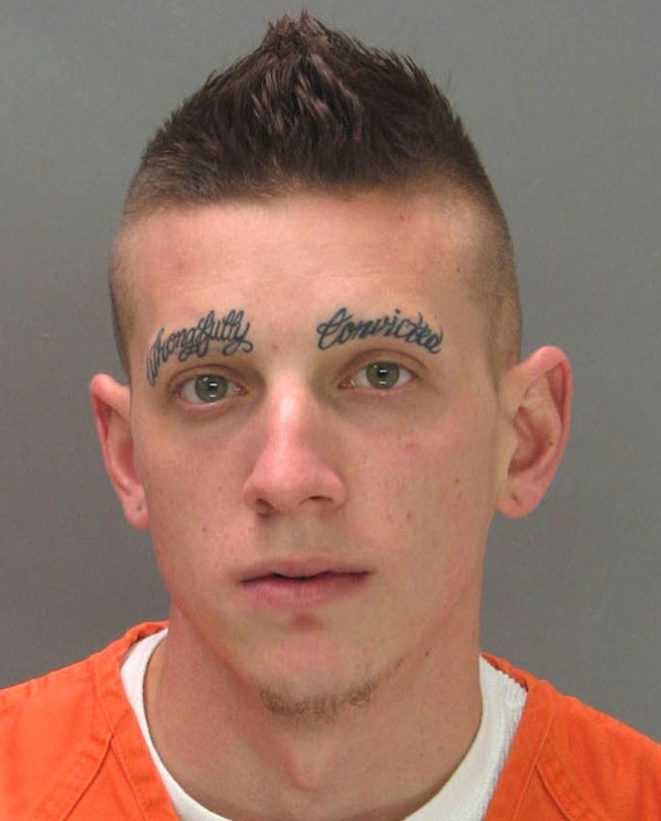 Man with "Wrongfully Convicted" tattooed above eyebrows in orange shirt, illustrating tattoo fail.