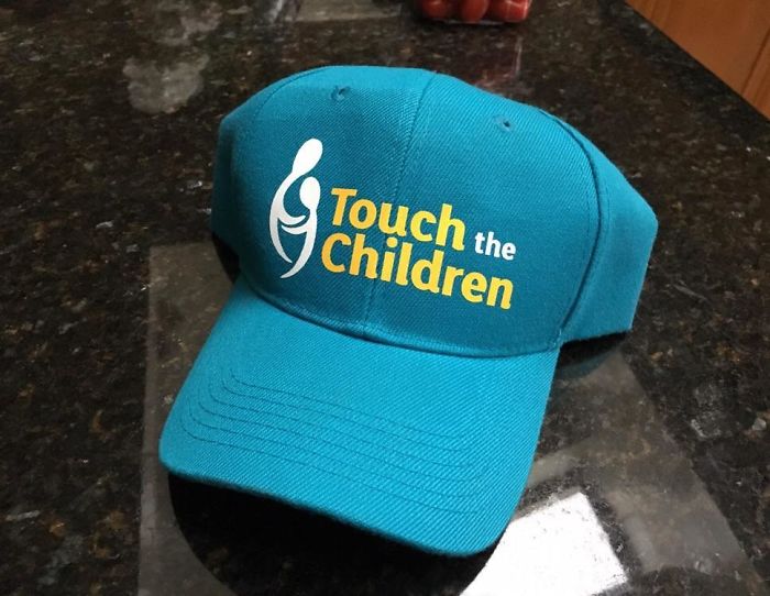 Turquoise cap with awkward text design, highlighting epic clothing disasters.