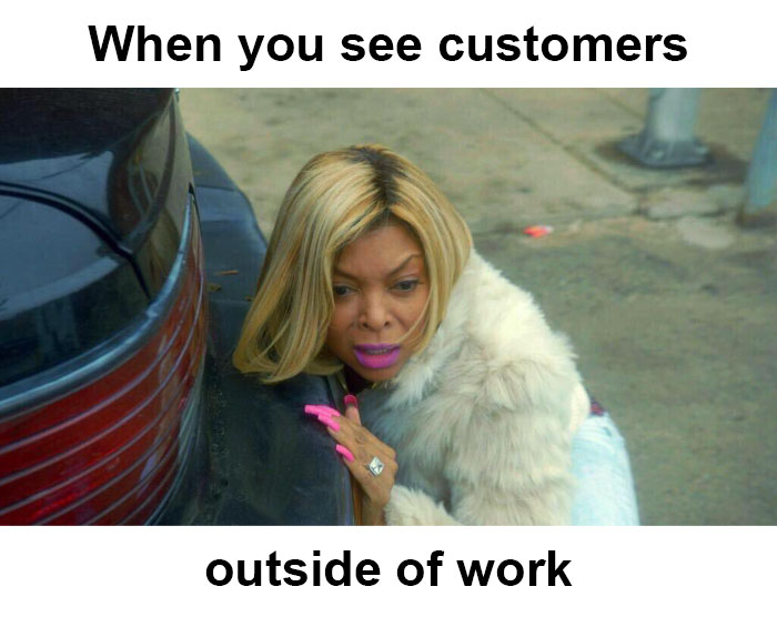 A woman hiding behind a car, surprised to see restaurant customers outside of work.