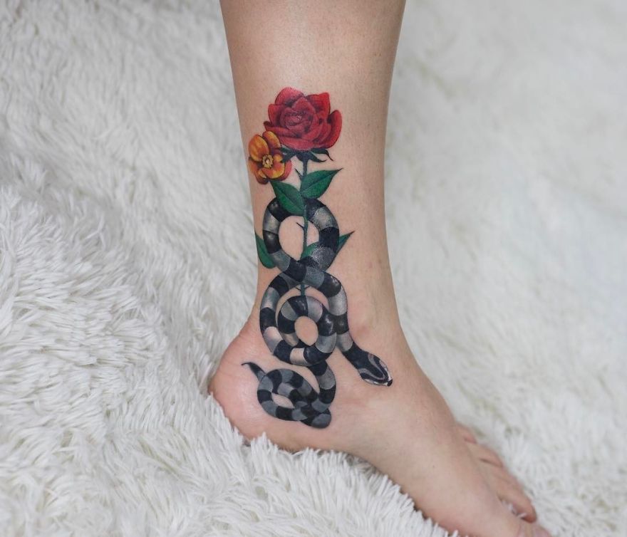 Snake tattoo with vibrant flowers on ankle by Korean artist.
