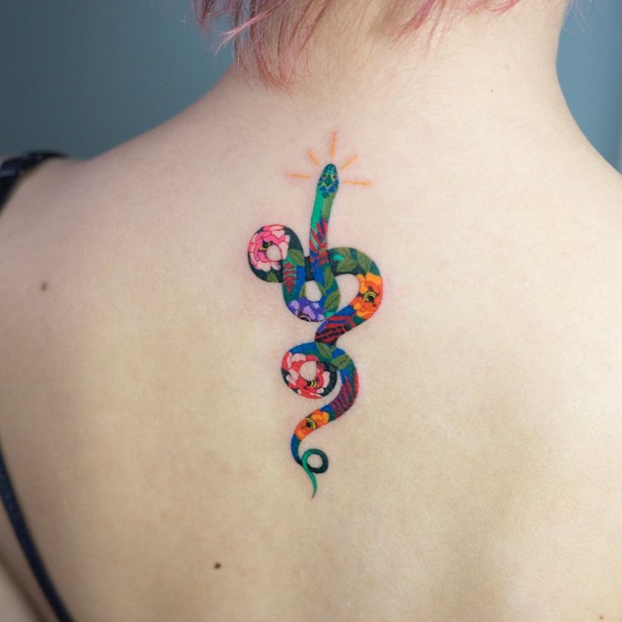 Colorful snake tattoo by Korean artist on upper back, showcasing intricate floral details.