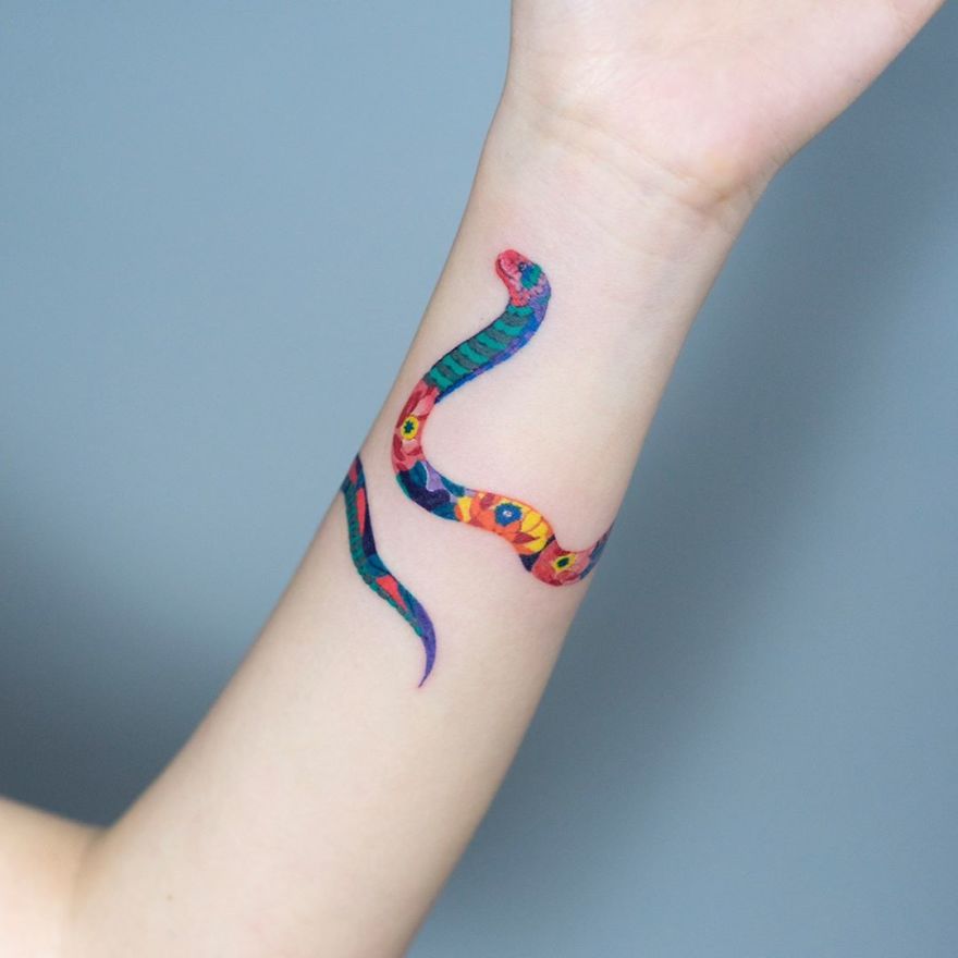 Snake tattoo art by Korean artist on forearm, featuring vibrant colors and intricate patterns.