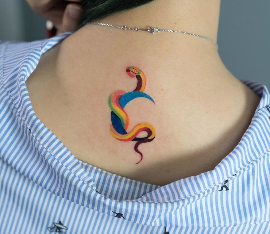 Vibrant snake tattoo by Korean artist on the back of a person wearing a striped shirt.