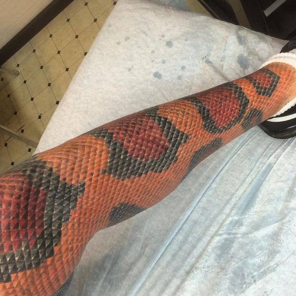 Leg tattoo designed with colorful scales resembling a snake, showcasing a unique tattoo fail.