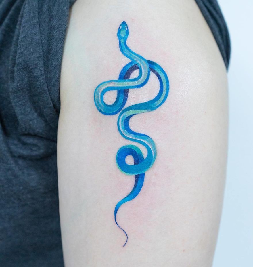 Blue snake tattoo by Korean artist on upper arm, showcasing unique style and intricate details.