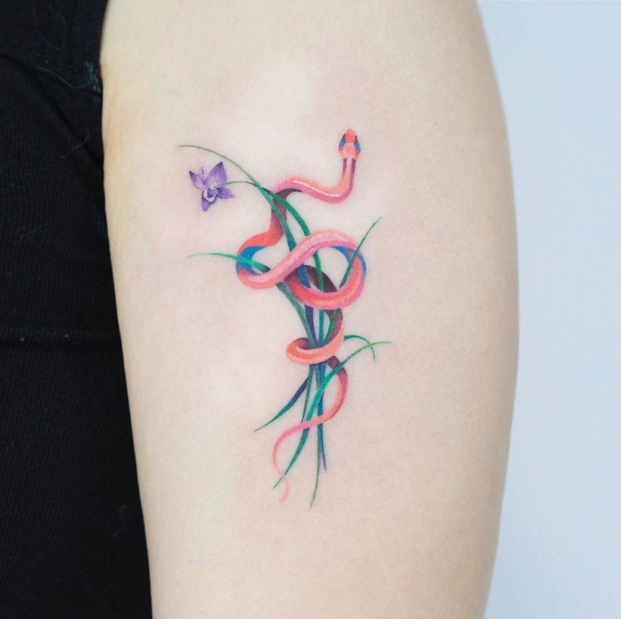 Korean artist's snake tattoo in vibrant colors with floral elements on an arm.