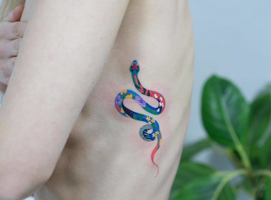 Colorful snake tattoo on skin by Korean artist, showcasing unique design with floral patterns.