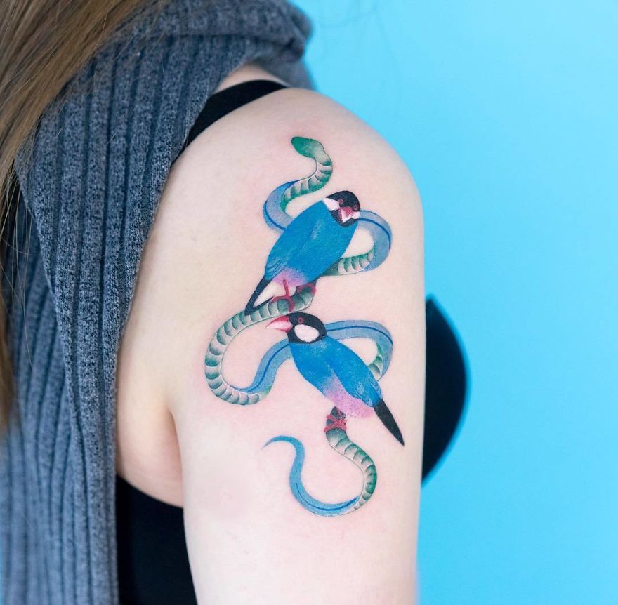 Korean artist's snake tattoo with vibrant birds on a person's arm, showcasing unique style.