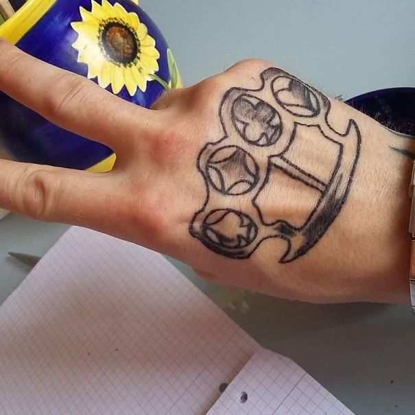 Hand with a poorly drawn tattoo resembling brass knuckles, showcasing a tattoo fail.