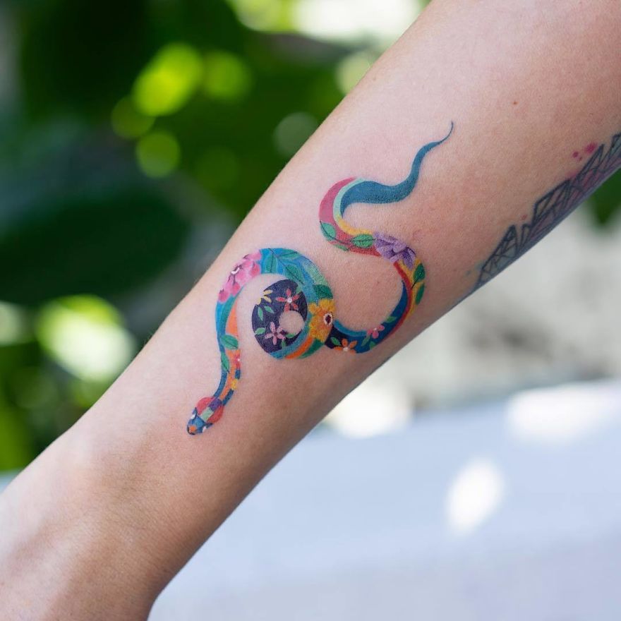Colorful snake tattoo on forearm by Korean artist, showcasing intricate and unique design elements.