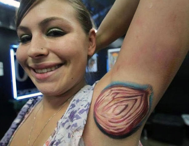 Woman with a bad tattoo of an onion on her armpit, smiling in a tattoo studio.