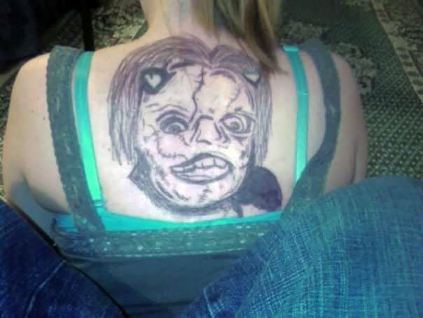 Back tattoo fail with a distorted face design, making it a cringe-worthy and laughable tattoo moment.