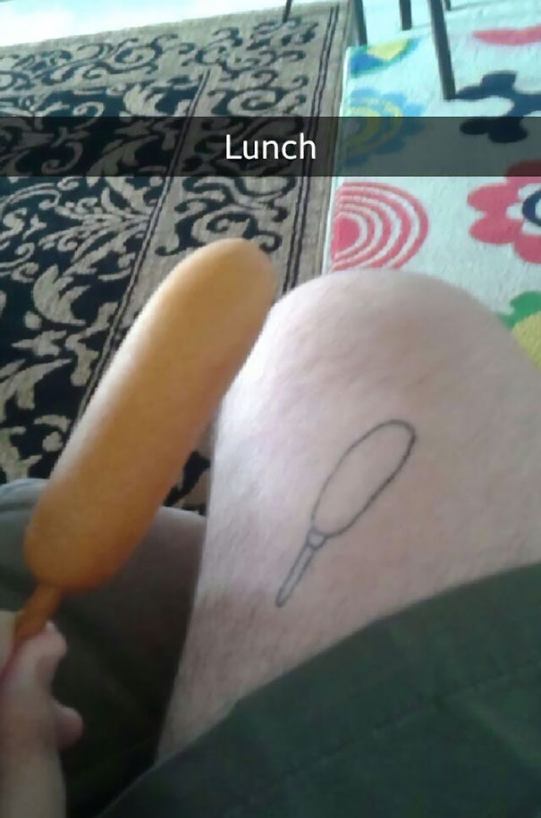 Bad tattoo fail depicting a simple corn dog design on a leg, with an actual corn dog held nearby.