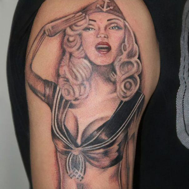 Tattoo fail of a pin-up style woman saluting with a sailor hat on an arm.