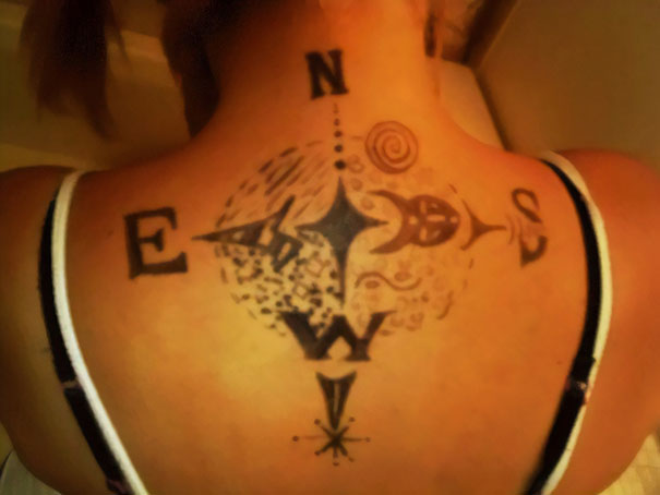 Back tattoo fail with compass design and misaligned letters N, S, E, W.