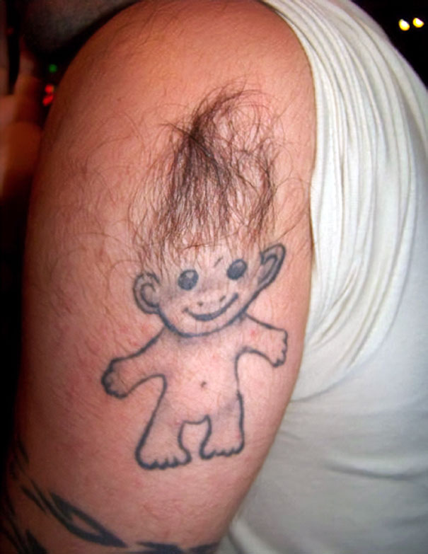 Hairy troll tattoo fail on arm, with real hair used as its top.