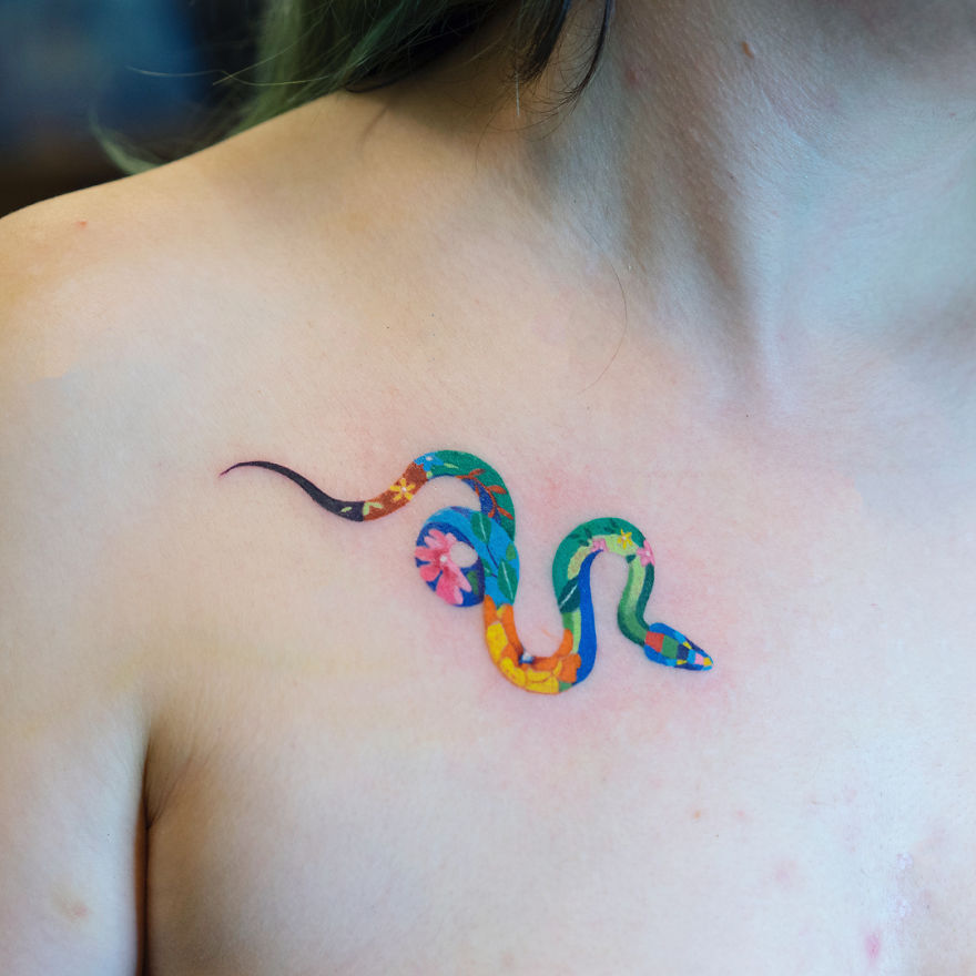 Colorful snake tattoo on chest by a Korean artist, featuring vibrant floral patterns.