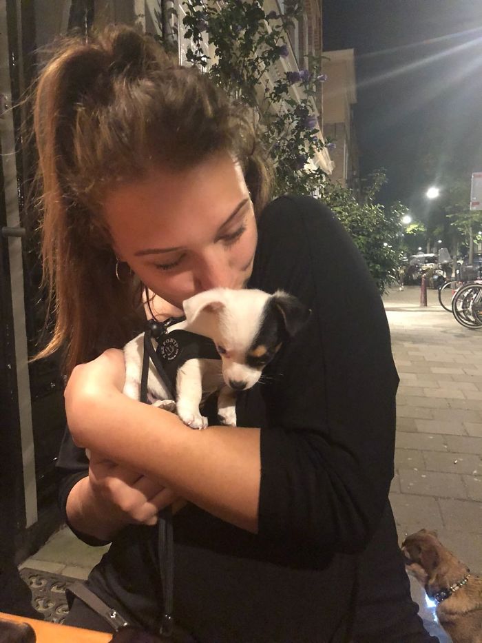 Young woman cuddling one of the cutest puppies on a city street at night.