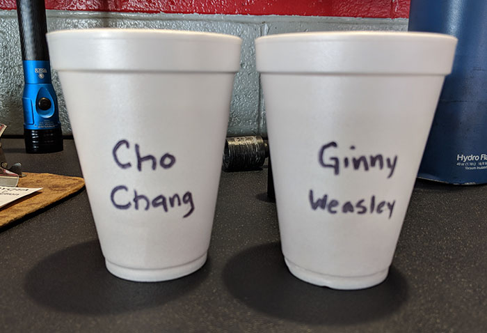 Two white foam cups on a table with coworker troll names highlighting Asian and white stereotypes.