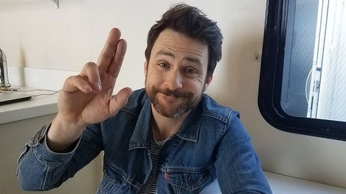 Charlie Day holding sign and smiling