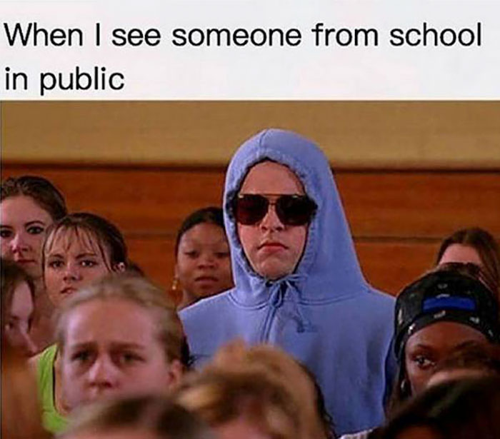 Person in blue hoodie and sunglasses trying to go unnoticed in a crowd, humorously capturing teacher memes.