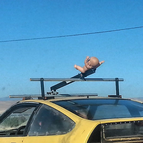 Just Drove By This Guy With This Baby Doll On His Car Roof. I'd Like To Think There's A Good Story Here. But He May Just Be Crazy