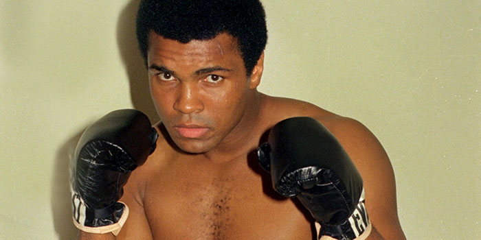 Mohammed Ali wearing gloves posing
