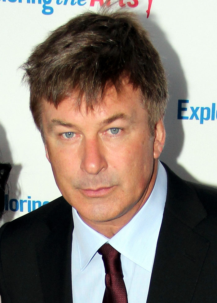 Alec Baldwin wearing suit and smiling