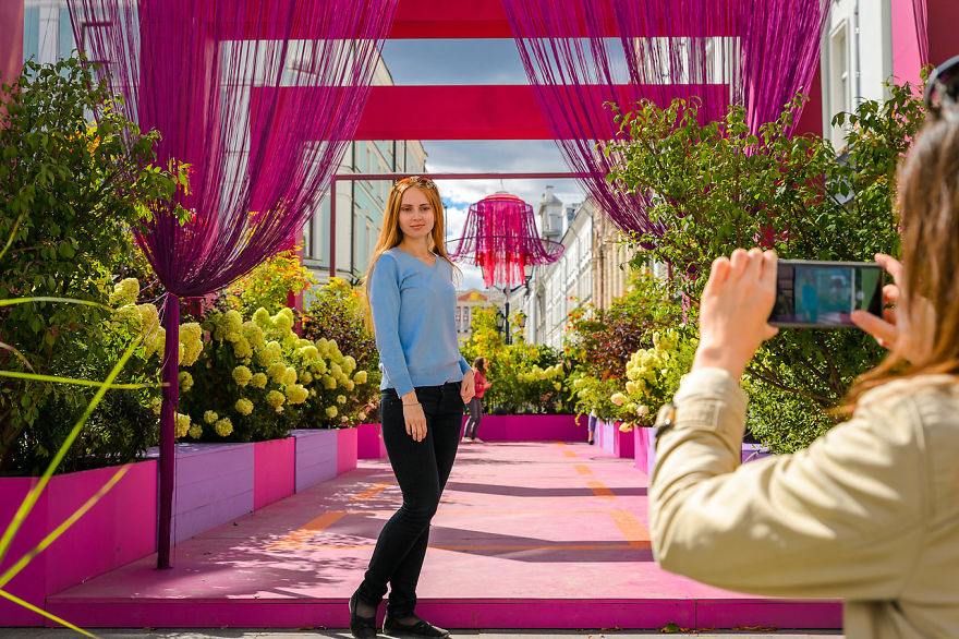 Young woman posing for a photo among vibrant flowers and decorations at the Flower Jam Festival in Moscow street.