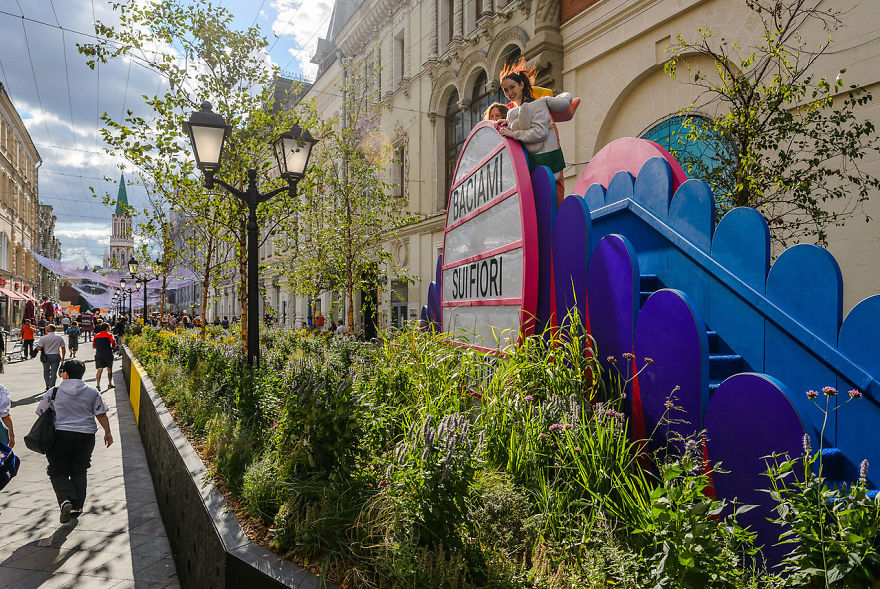 Colorful outdoor floral display with people walking along a street during Flower Jam Festival in Moscow.