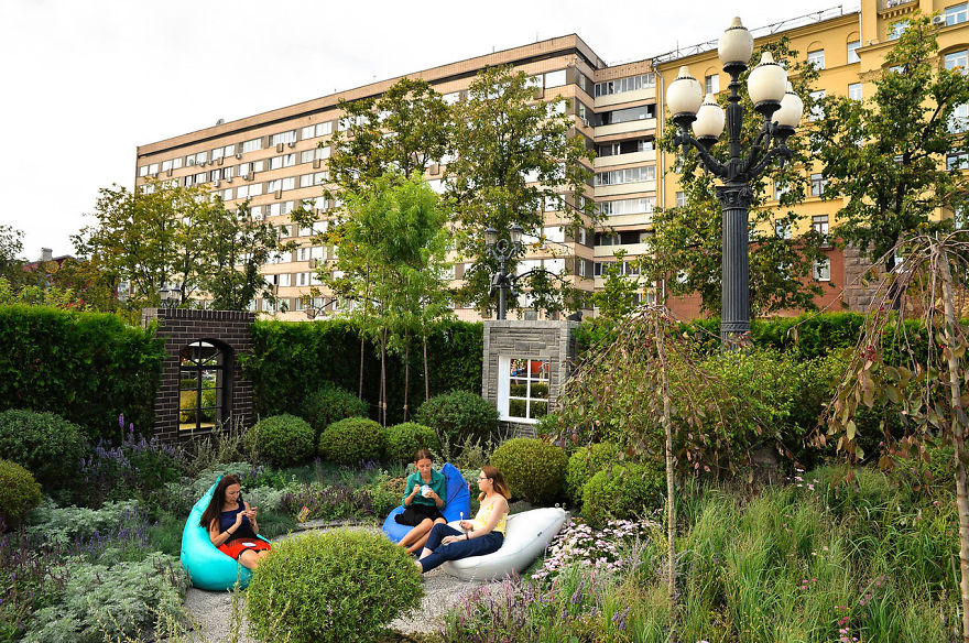 Three women sitting on bean bags surrounded by flowers and greenery at the Flower Jam Festival in Moscow.