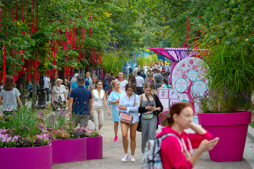 Crowd enjoying the vibrant Flower Jam Festival in Moscow with colorful flowers and greenery along the pathway.
