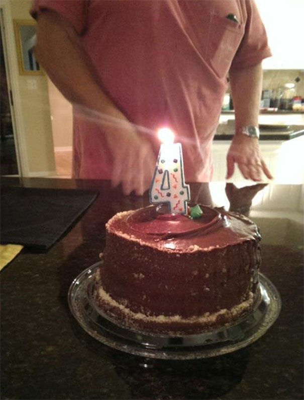 Funny dad celebrating with a chocolate cake featuring a numeral four candle.