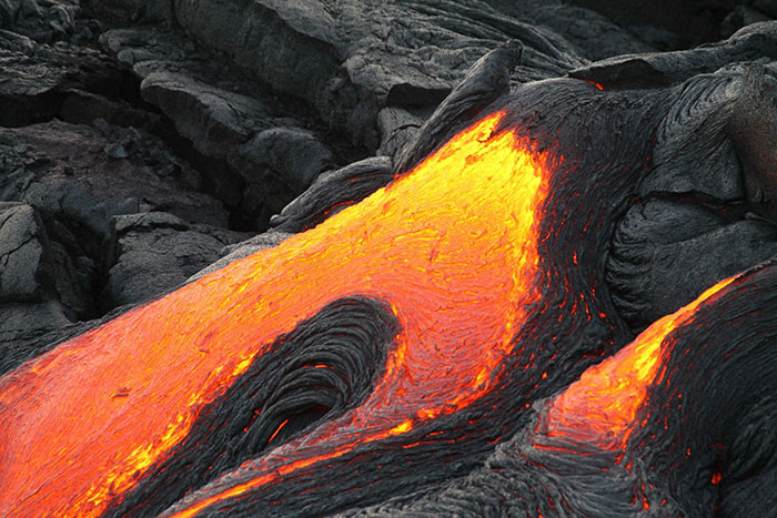 Molten lava flowing over dark volcanic rock, illustrating geological changes to Earth in the next trillion years.