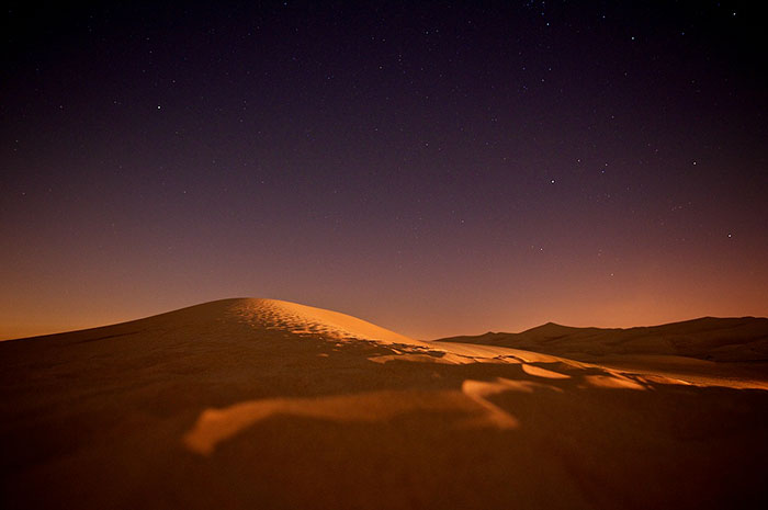 Desert landscape under a starry night sky illustrating things that will happen to Earth in the next trillion years.