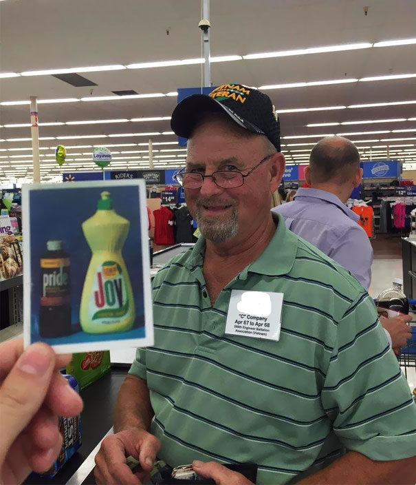 Smiling dad at the store with a humorous photo of cleaning products titled "Pride" and "Joy."